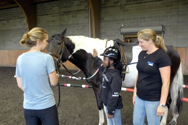 Southampton Intermediate School Principal Timothy Frazier gets a riding lesson from the girls at their graduation from the program on Monday at Wollfer Stables in Sagaponack. DANA SHAW