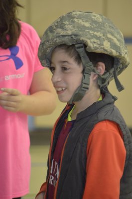 Remsenburg-Speonk Elementary School fourth-grader Manuel Lopez demonstrates a helmet used by members of the ANG's 106th Rescue Wing and prepared care packages on Thursday. BY ERIN MCKINLEY