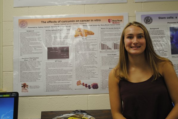 Sydney Caldwell, a junior at Hampton Bays High School, stands next to a poster for her science research project. AMANDA BERNOCCO