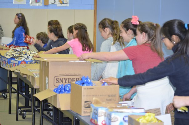 Fifth graders at Remsenburg-Speonk Elementary Schoolhelps stuff care packages for soldiers over seas. BY ERIN MCKINLEY