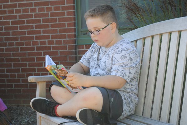 Bruce Phillips III reads a book in the East Quogue reading garden. AMANDA BERNOCCO