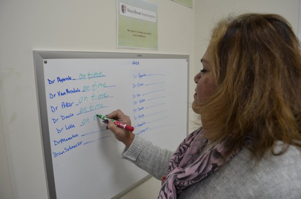 Westhampton Primary Care Center Site Administrator Maria Barlowe informing patients which doctors are in that day on a white board displayed in the waiting room. ANISAH ABDULLAH