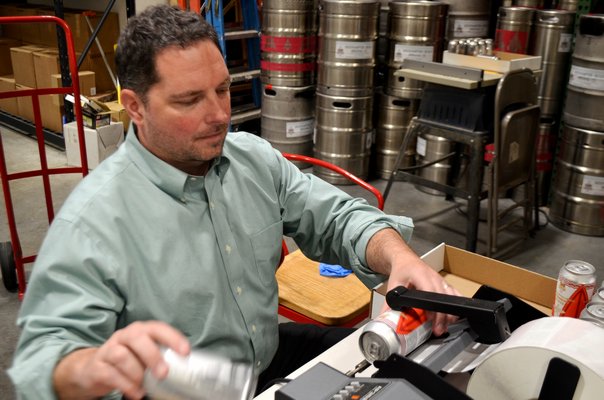 Brian Sckipp manually labeling the Strawberry Blonde beer cans. ANISAH ABDULLAH
