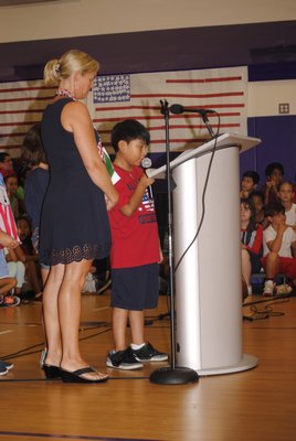 Amy McNamara watches as her student, Giovanni Tzitzimititla, talks about the terrorist attacks on September 11, 2001, during a flag ceremony at Hampton Bays Elementary School. AMANDA BERNOCCO