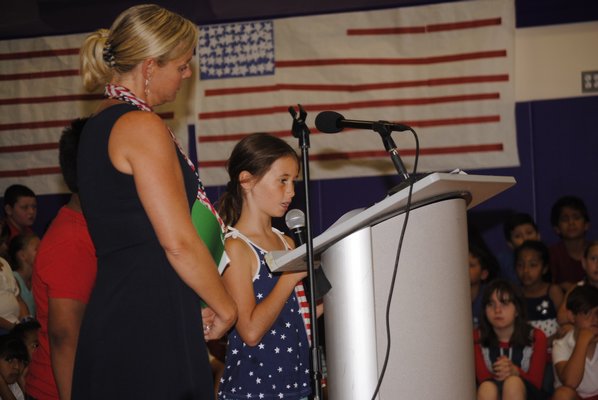 Amy McNamara watches as one of her students, Lalia DeRosa, talks about the terrorist attacks on September 11, 2001, during a flag ceremony at Hampton Bays Elementary School. AMANDA BERNOCCO