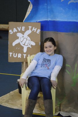 Kristina Vacaliere shows off a "Save the Turtles" sign made as a prop for their Odyssey of the Mind presentation. BY ERIN MCKINLEY
