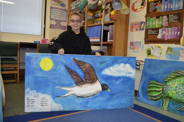 Kevin Smith, 11, shows a celing tile he helped paint at Westhampton Beach Elementary School. BY ERIN MCKINLEY