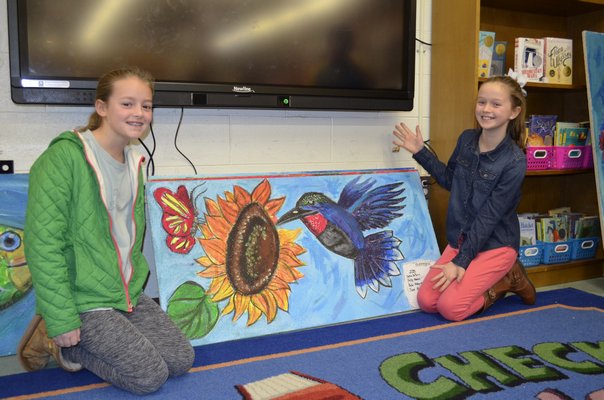 Haley Waszkelewicz, 10, and Jane Atkinson, 10, from left, show a celing tile they helped paint at Westhampton Beach Elementary School. BY ERIN MCKINLEY