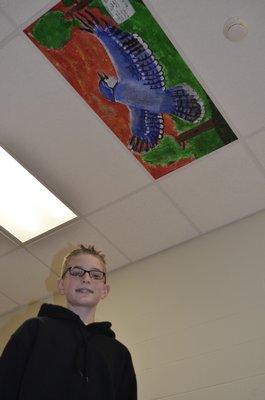 Kevin Smith, 11with a ceiling tile painted last year that is on display at Westhampton Beach Elementary School. BY ERIN MCKINLEY