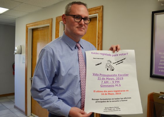 Hampton Bays Superintendent of Schools Lars Clemensen holding a voter registration poster in Spanish that is displayed throughout the school district. ANISAH ABDULLAH