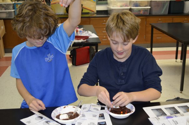 East Quogue Elementary School Astronomy Club members Mark Sirico, left and Dan Stark tested the impact of foreign objects on the moon's surface at last Thursday's meeting using chocolate pudding. ALEXA GORMAN