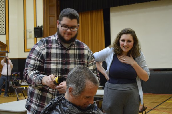 Bridgehampton School senior Dan Denton shaves teacher John Reilly's head on Friday while fellow senior Hayley Lund looks on. ALYSSA MELILLO