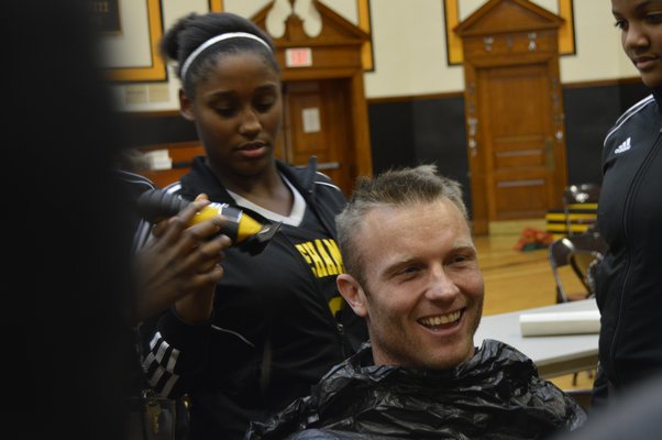 Members of the Bridgehampton School girls' basketball team shave off District Athletic Director Eric Bramoff's hair on Friday. ALYSSA MELILLO