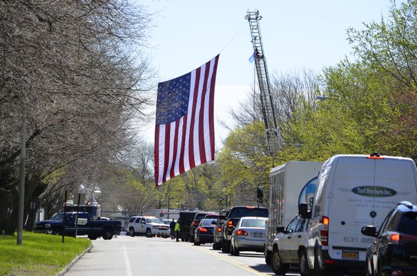 Fire trucks hung an American flag above Hill Street in Southampton to honor the life and service of Edward Corrigan. ANISAH ABDULLAH