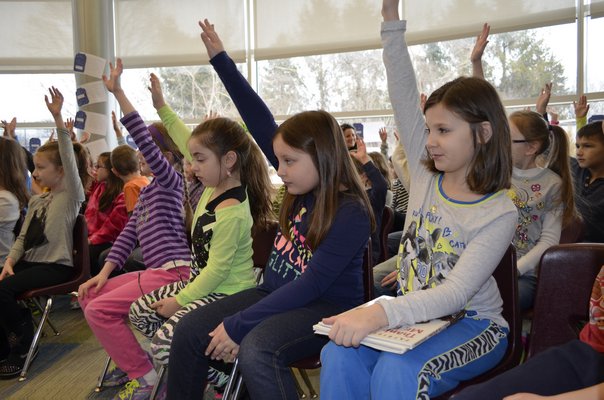 Colleen Carroll, left, Alyssa Rando, Kellie Langa and Amanda Seglignan raise their hands during a presentation by Patricia Polacco, a children's author and illustrater, at Tuttle Avenue School Friday morning. ALEXA GORMAN