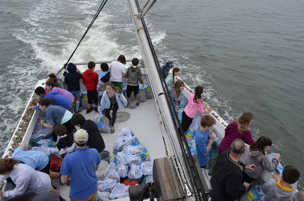 East Quogue sixth-graders tossed clams into Tiana Bay as part of the Shinnecock Bay Restoration Project. ALEXA GORMAN