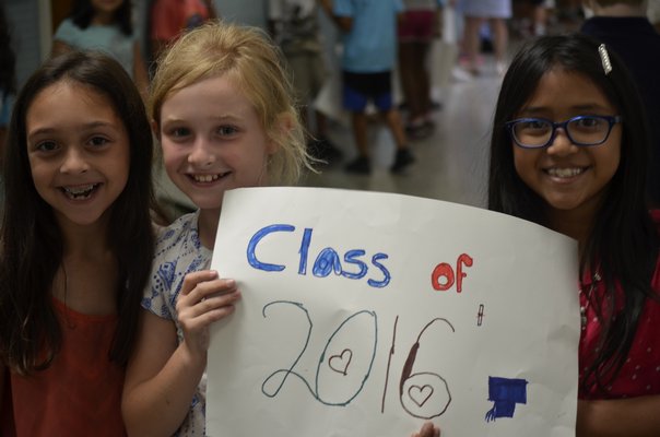 Students Mia Valenzuela, 9, left, Adelina Scott, 9, and Rosaria Set, 9, wait to congratulate graduating high school seniors. BY ERIN MCKINLEY