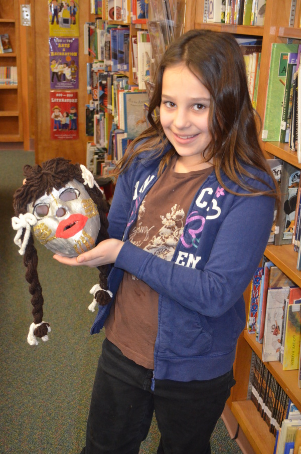Fifth grader Gasmine Agme displays an art mask that was in the time capsule. ERIN MCKINLEY