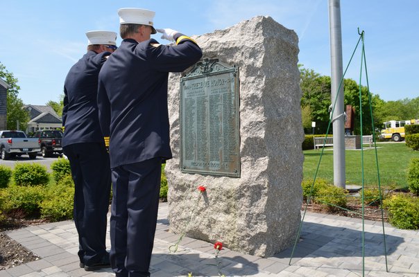 Members of the Quogue Fire Department salute the fallen soldiers listed on the village's memorial. Alexa Gorman