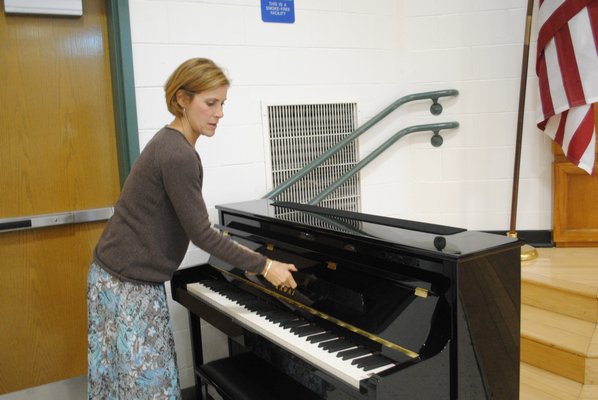 Penni Russo, an instrumental teacher at East Quogue School, opens the donated piano. AMANDA BERNOCCO