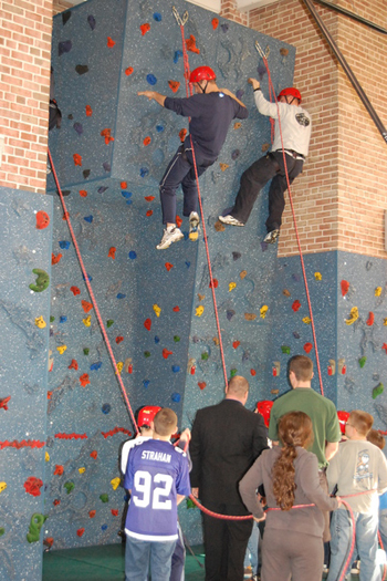 Elementary School principal Ron Masera, left, and teacher Sean Montpetit climb up the wall with the help of elementary school students.