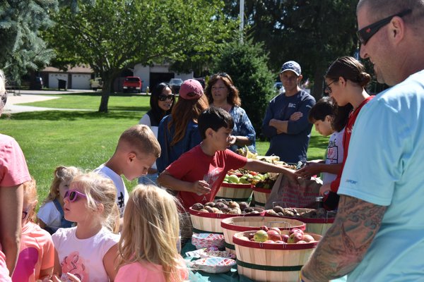 Easport Elementary students fill bags with produce from their school's farm at Saturday's famer's market. CHRIS PERAINO