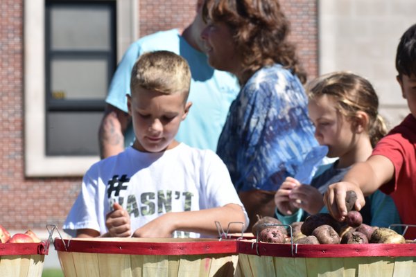 Easport Elementary students fill bags with produce from their school's farm at Satur
