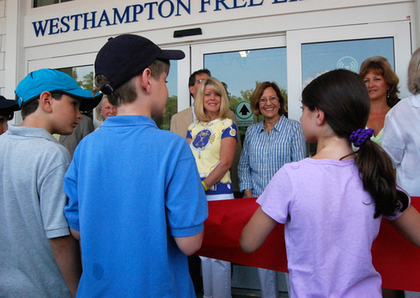 Kids hold up the ribbon as Library trustees Karen Andrews, right, Jane Lapple and Maria Moore, before the Westhampton Free Library opened on Saturday.
