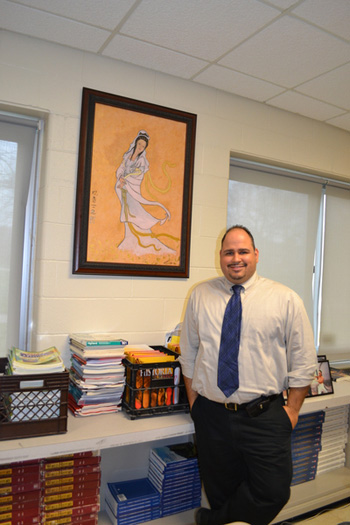 Hampton Bays High School history teacher PJ Lopez stands alongside a painting that a former student painted for him.