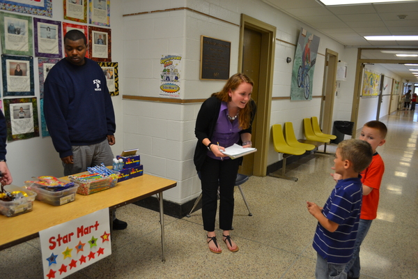 James McClease, a student at the Eastport South Manor Junior-Senior High School, waits to help students at the Dayton Avenue School at the "Star Mart," as his aide Alyssa Ruszkowski takes down their names.