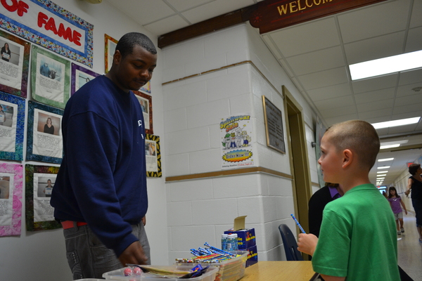A second grade student at the South Street school receives a prize from the Star Mart from special education student James McClease.
