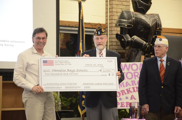 Richard Joslin, pictured left, accepts a check for $2,000 at Tuesday night's Hampton Bays Board of Education meeting from Commander Richard Steiber, center, and William Hues, right, on behalf of the American Legion Hand-Aldrich Post 924, to replace the flag pole in front of the elementary school that was blown down during a snow storm in February. GREG WEHNER