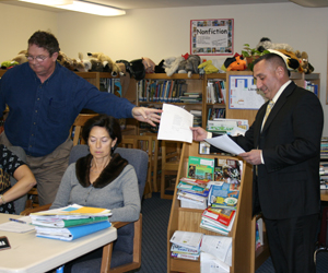 Remsenburg/Speonk School Board member Joel Petersen hands Charles Russo, the superintendent of East Moriches School District, a paper. Remsenburg/Speonk Superintendent Katherine Salomone listens.  JESSICA DINAPOLI