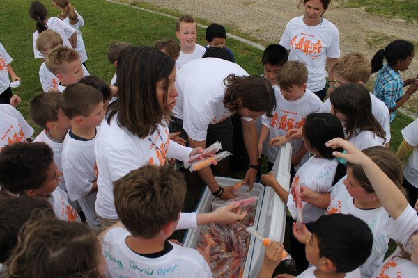 Third graders swarm around Westhampton Beach Elementary School Principal Lisa Slover, left, and physical education teacher Drew Peters after participating in the school's Amazing Race Obstacle Course on Friday afternoon. KYLE CAMPBELL