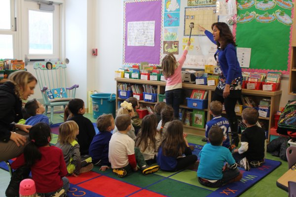 Lisa Wells helps her kindergartenders learn the days of the week during their first day in the new classroom at the Tuttle Avenue School. BY CAROL MORAN