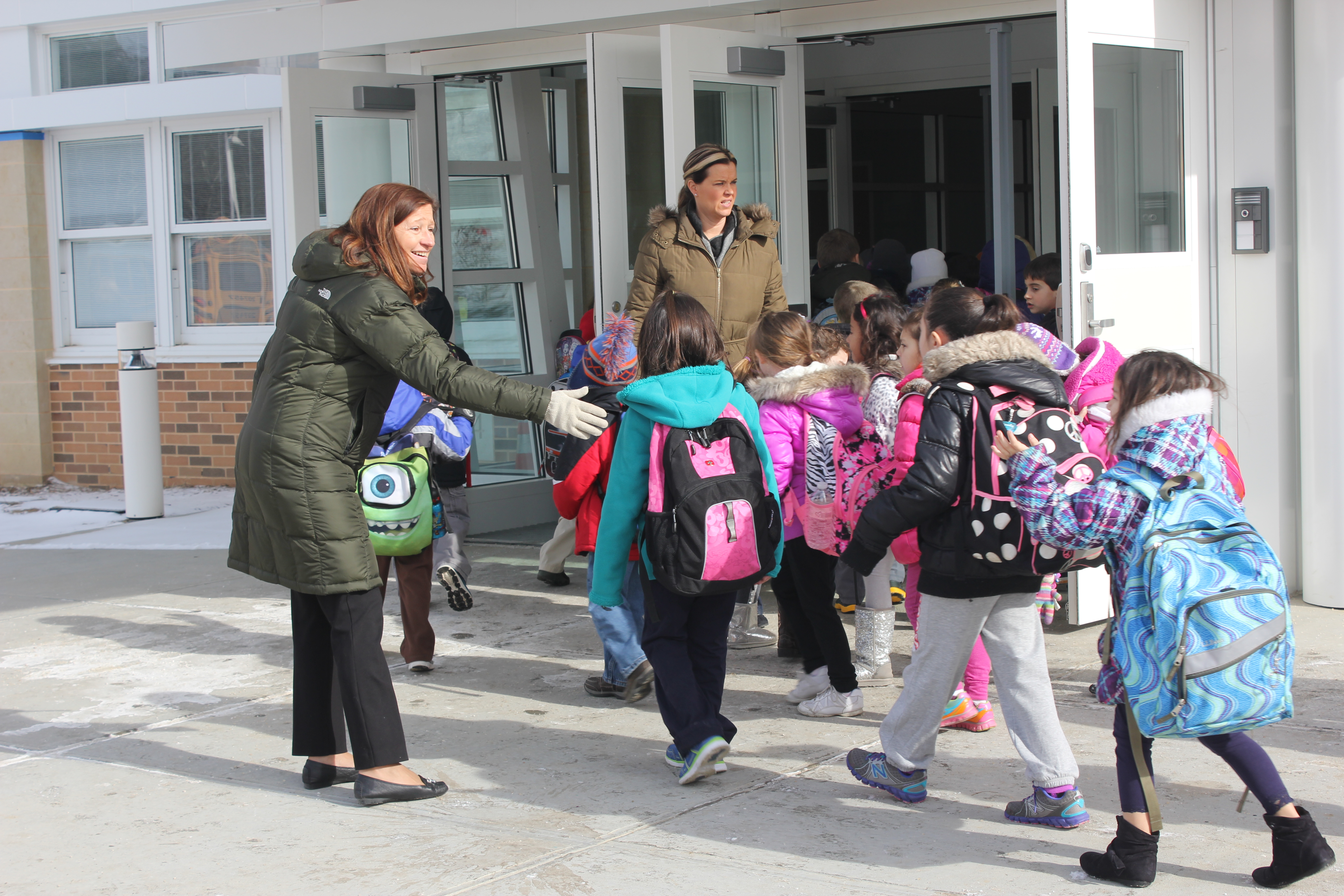 Karen Koliadko, principal of the Tuttle Avenue School, greets children as they arrive for their first week of classes in the new building. BY CAROL MORAN