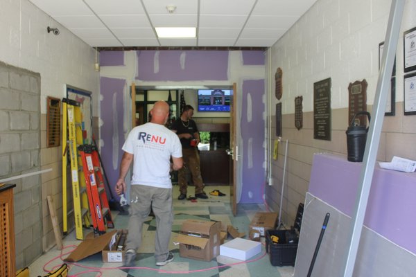 Glen Coon, a junior with Rocky Point-based Renu Contracting, works on installing the double doors in the school's main lobby. VALERIE GORDON