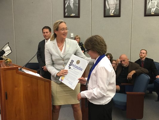 Suffolk County Legislator Bridget Fleming presents Daniel Stark with a proclamation for his work on his project.   COURTESY ROBERT LONG