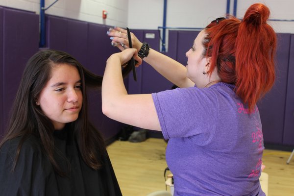 Jessica Roth of Center Moriches cuts Hampton Bays eighth grader Melany Nives's hair during the Hampton Bays "Hair Happening" to benefit Locks of Love on Monday. KYLE CAMPBELL