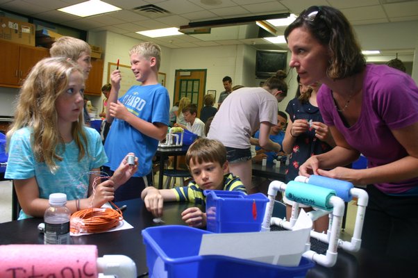 East Quogue resident Ellen Murphree, 11, left, talks to East Quogue resident Dianna Gobler about a propeller for an underwater remote operated vehicle. Murphree's father, Brad Murphree, instructed a class of more than 30 4th and 5th graders on how to build the vehicles as part of a summer ocean explorer's camp at East Quogue Elementary School, 6 Central Ave., East Quogue. KYLE CAMPBELL