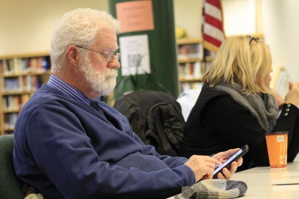 Westhampton Beach Board of Education Jim Hulme thumbs through his phone during Monday night's meeting. KYLE CAMPBELL