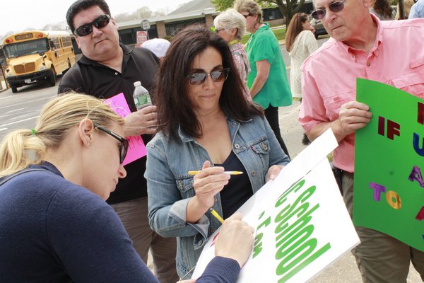 From left, Amy Staugasser of Bablyon, Kevin Daly of Patchogue, Dawn Manzi of Westhampton and Patrick Smith of South Jamesport sign petitions requesting that the Westhampton Beach School Board allow 12-year-old Aiden Killoran, a Remsenburg-Speonk student with Downs Syndrome, to attend the district's middle school next year. KYLE CAMPBELL