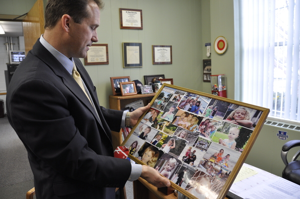 Newly hired Remsenburg/Speonk Superintendent of Schools Dr. Ronald Masera shows a collage of family photos that he has hanging in his office on Tuesday afternoon.