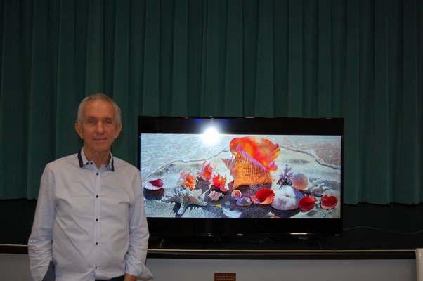 Charles Wildbank in front of a display of his paintings at Our Lady of the Hamptons Regional Catholic School. JON WINKLER
