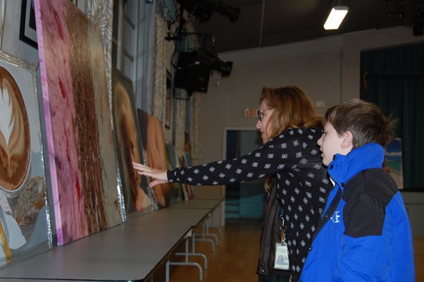 Special Education Teacher Shelley Borkoski, center, showing Luke David paintings by Charles Wildbank at Our Lady of the Hamptons Regional Catholic School. JON WINKLER