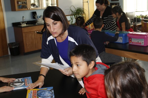 Ms. Laureen Andria helps out first grader Juan Saquic with some research materials. KATE RIGA