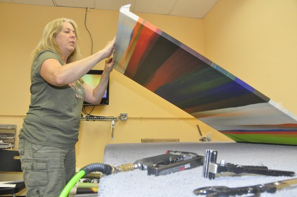 Production Manager Annie Scheuring hand-stretches a digital thermal print at Modern Digital Canvas. MICHELLE TRAURING