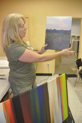 Production Manager Annie Scheuring shows off two finished pieces, the smaller of which was printed from an iPhone photo. MICHELLE TRAURING