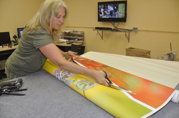 Production Manager Annie Scheuring divides two digital thermal prints before hand-stretching them over frames. MICHELLE TRAURING