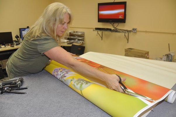 Production Manager Annie Scheuring divides two digital thermal prints before hand-stretching them over frames. MICHELLE TRAURING